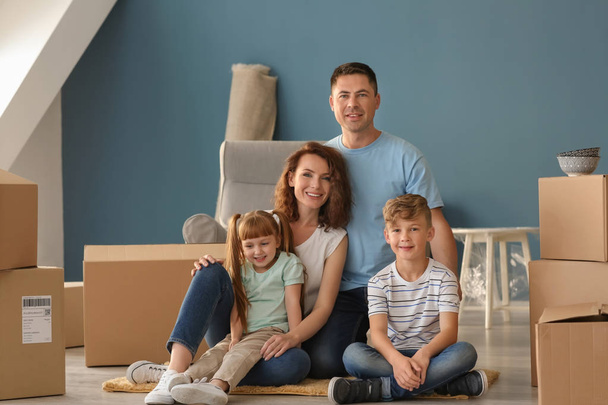 Happy family with cardboard boxes indoors. Moving into new house - Photo, Image