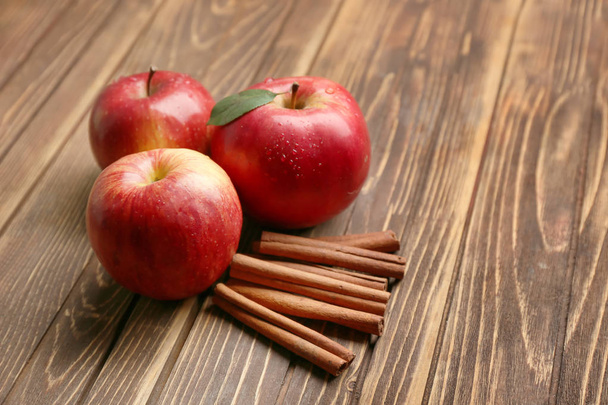 Свежие спелые яблоки и корица на деревянном столе
 - Фото, изображение