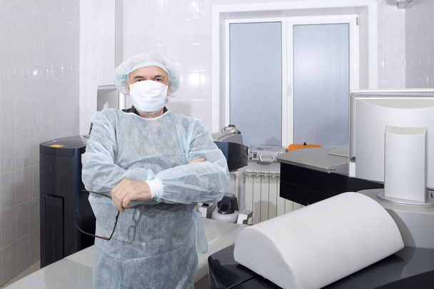 A male surgeon is standing near the operating table before the beginning of an operation for vision correction - Photo, Image
