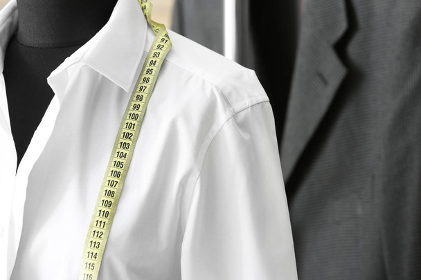Mannequin with custom tailored shirt and measuring tape in atelier, closeup - Foto, afbeelding