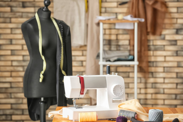 Kleermaker van werkplek met de naaimachine en mannequin in atelier - Foto, afbeelding