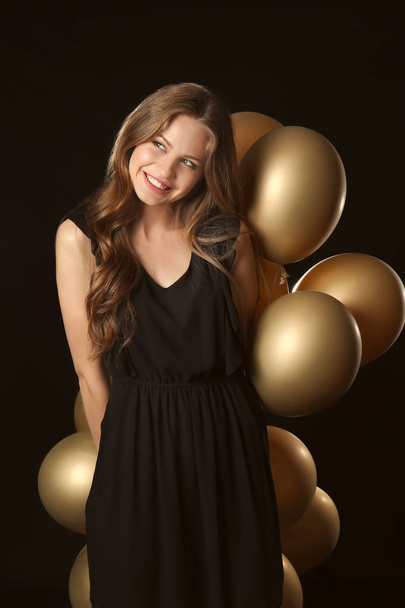Beautiful young woman with balloons on dark background - Fotó, kép
