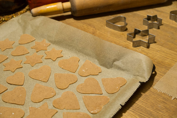 Ev yapımı Gingerbread çerezleri kesme formlar ve zencefilli kurabiye hamur kabartma kağıt pişirme için hazır - Fotoğraf, Görsel