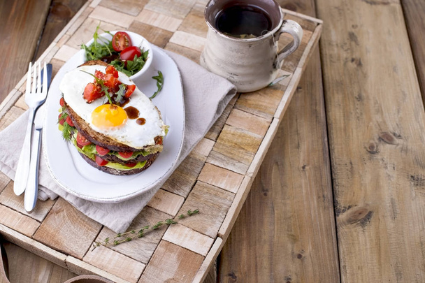Toast aus einem Kornbrot mit Käse, Tomaten und Ei. Vegetarische Kost. auf einem weißen Teller und einem hölzernen Hintergrund. nützliches Frühstück. Freiraum zum Schreiben von Texten. - Foto, Bild