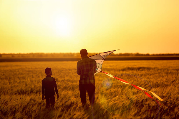 Boldog apa és fia, repülő kite területén a naplemente - Fotó, kép