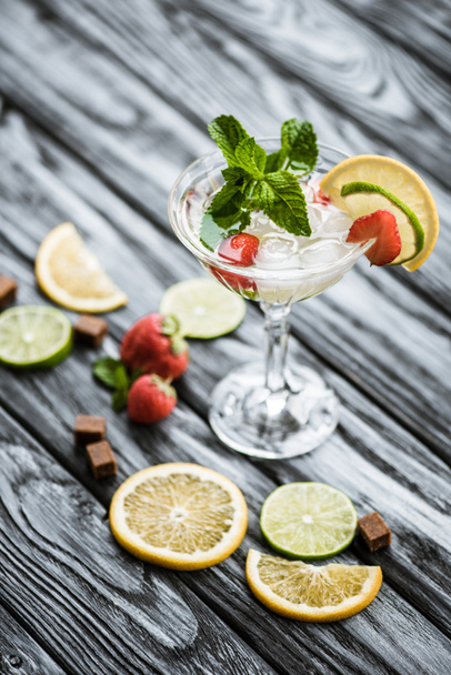 close-up view of fresh summer cocktail with mint and fruits in glass on wooden table - Foto, Imagen