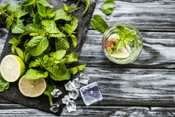 top view of glass with fresh cold strawberry and kiwi mojito on wooden table  - Фото, зображення