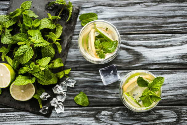 top view of glasses with mojito and fresh ingredients on wooden surface  - Photo, Image
