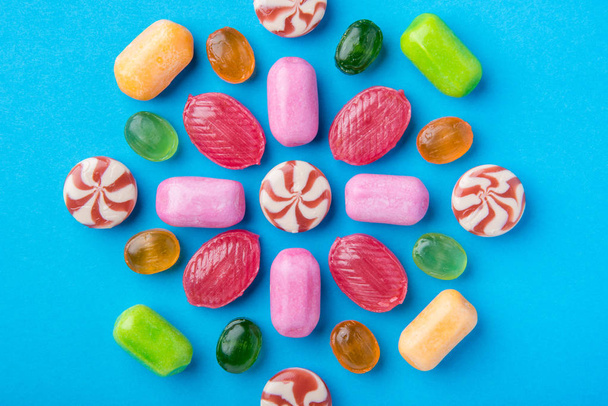 Many multicolored delicious caramel candies on a blue background - Foto, afbeelding