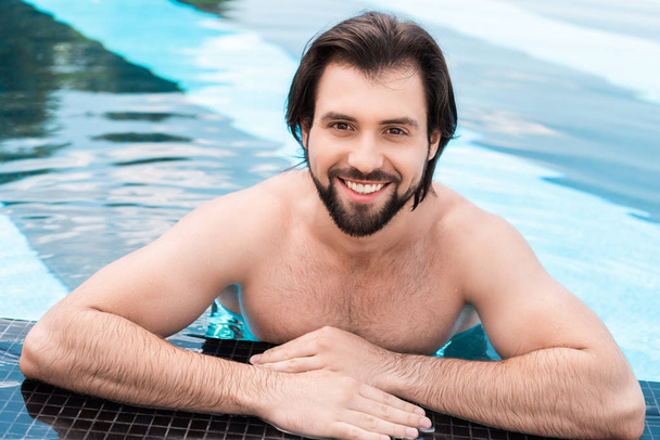 бородатий усміхнений чоловік у басейні дивиться на камеру
 - Фото, зображення