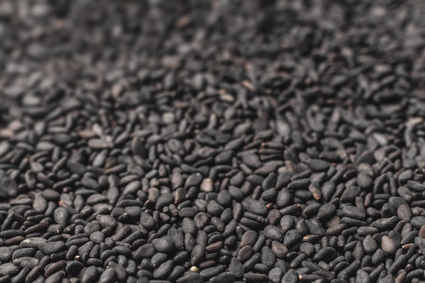 schwarze Sesamsamen. Hintergrund von schwarzen Bohnen, die sich in weichen Fokus verwandeln. Zusatzstoffe zum Essen - Sesam. gesunde Ernährung. - Foto, Bild
