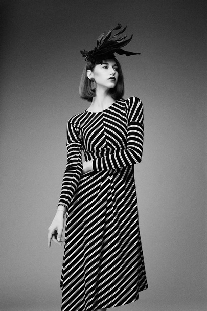 black and white photo of gorgeous young woman in elegant headdress posing against studio background   - Zdjęcie, obraz