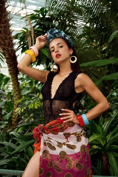 attractive young woman in elegant headdress with various bracelets posing outdoors  - 写真・画像