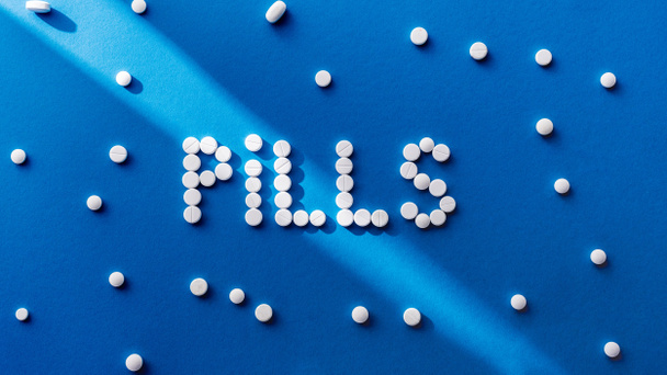 vista dall'alto di pillole lettering da compresse bianche su sfondo blu
  - Foto, immagini