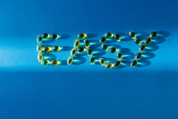 bovenaanzicht van belettering gemakkelijk door pillen op blauwe achtergrond met zonlicht  - Foto, afbeelding
