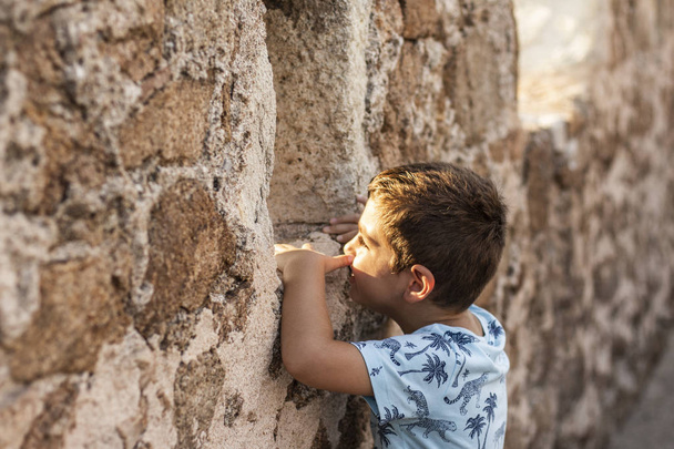 Niño mirando a través de la pared de un castillo
 - Foto, imagen