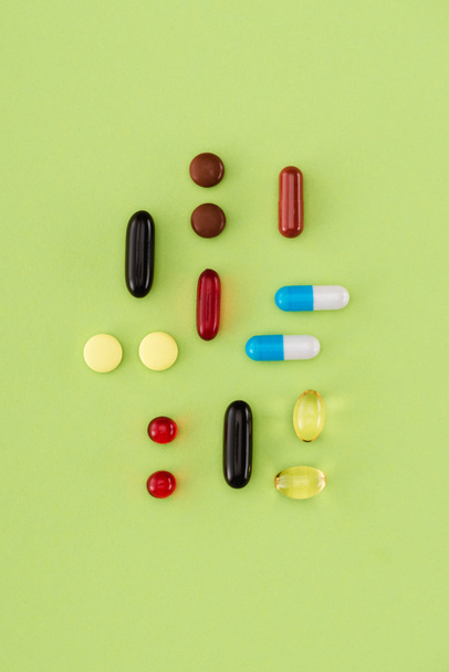 elevated view of arranged various pills on green background - Photo, Image