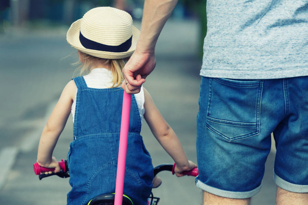 Father is teaching his daughter to ride a bicycle. - 写真・画像
