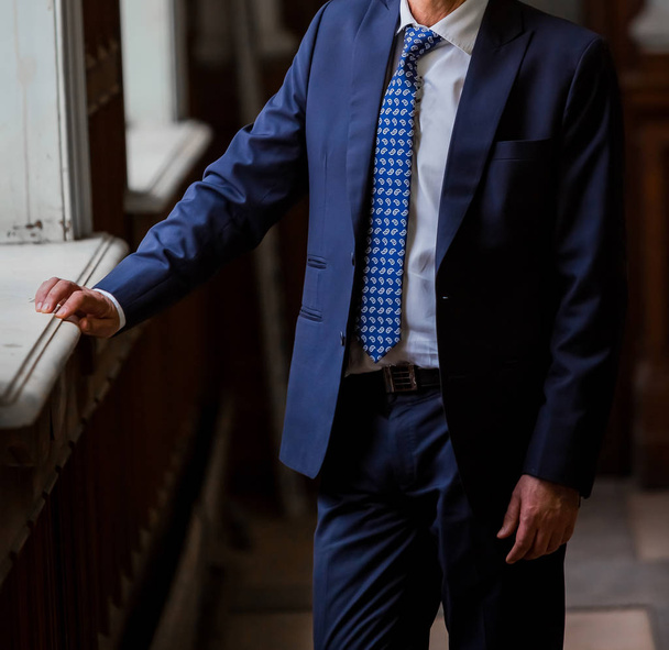 Close-up cortado mãos caucasianas e braços de homem de negócios em um terno com gravata azul
 - Foto, Imagem