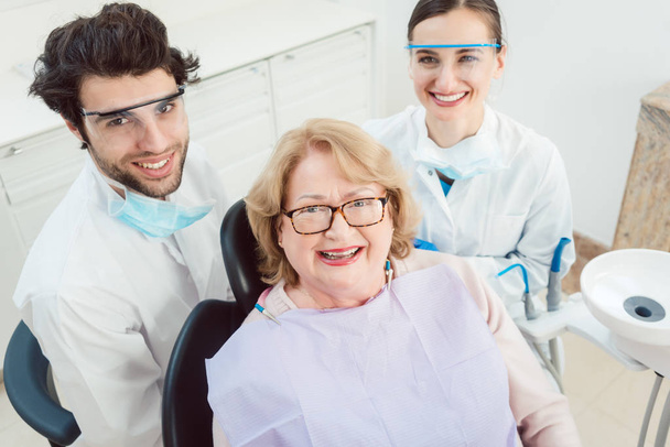 Dentyści i pacjent w gabinecie patrząc na kamery - Zdjęcie, obraz