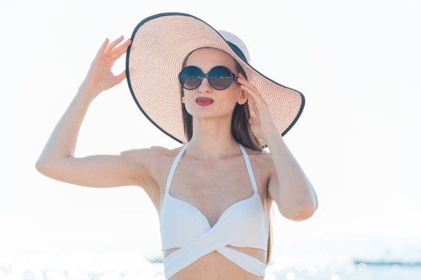 Жінка з сонячним капелюхом стоїть на пляжі
 - Фото, зображення