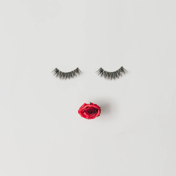 Cara creativa de mujer hecha de pestañas y labios de flor de rosa roja, concepto de belleza mínima
  - Foto, imagen