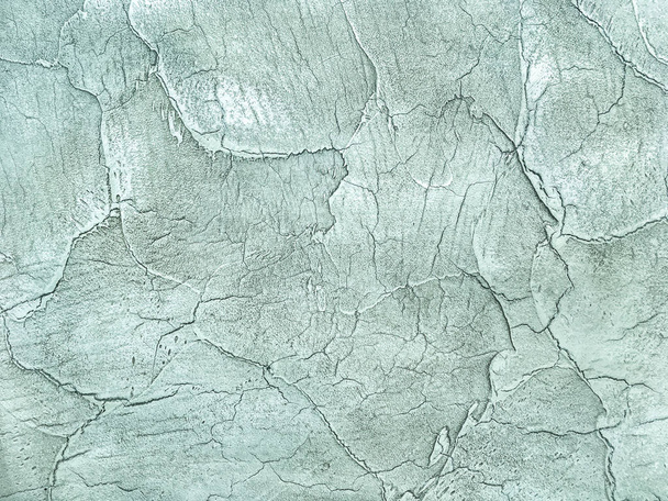 Texture decorative light green plaster imitating the old peeling wall. Obsolete turquoise cracked background, closeup - Photo, Image