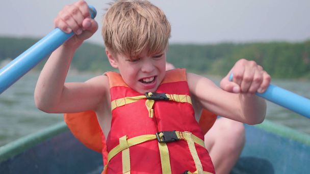 Экстремальный спорт. Парень плавает на лодке. Подросток самостоятельно управляет лодкой с помощью весел
 - Фото, изображение