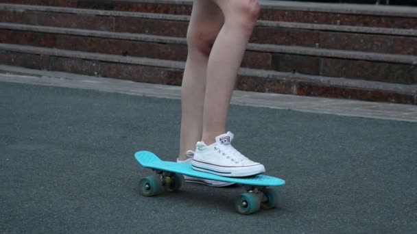 skateboarding, leisure, extreme sport and people concept - teenage girl legs riding short modern cruiser skateboard on road - Footage, Video