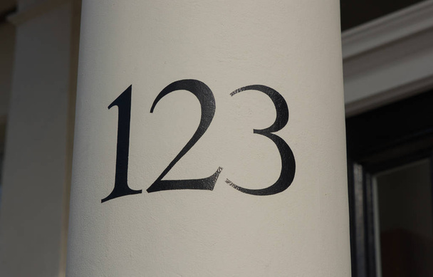 Número de casa pintado con negro sobre columna blanca por puerta en Londres, Inglaterra. Número ciento veintitrés, o uno, dos, tres. 123
. - Foto, imagen