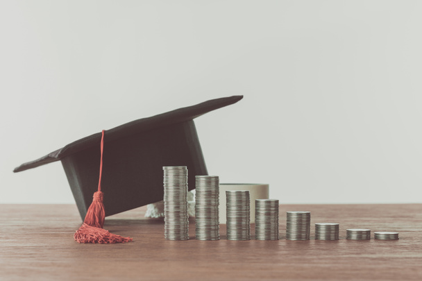 stacks of coins and graduation cap on wooden table, saving concept - Photo, Image