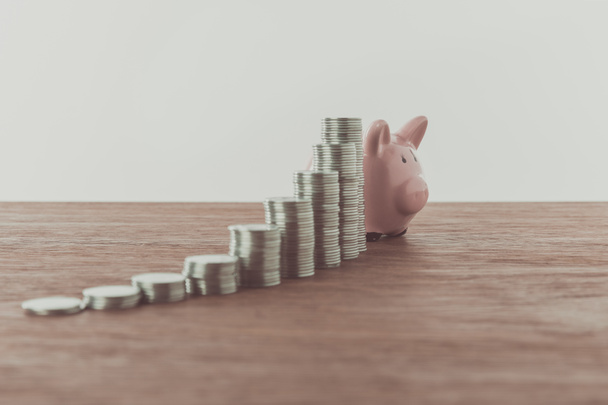 stacks of coins and piggy bank on wooden table, saving concept - Photo, Image