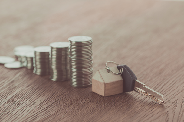 ключ с безделушкой возле стопок монет на деревянном столе, концепция экономии
 - Фото, изображение