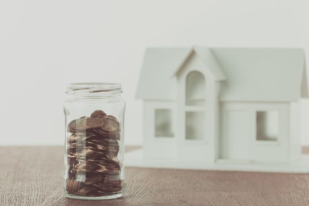 jar of coins and small wooden house on table, saving concept - Photo, Image