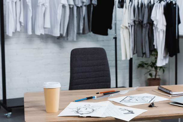 селективное фокусирование чашки кофе и картин на рабочем столе в студии дизайна одежды
  - Фото, изображение