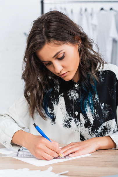 mujer diseñadora de moda pintura en mesa de trabajo en estudio de diseño de ropa
 - Foto, Imagen