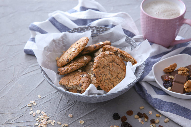 Taça de vime com deliciosos biscoitos de aveia e xícara de café na mesa
 - Foto, Imagem