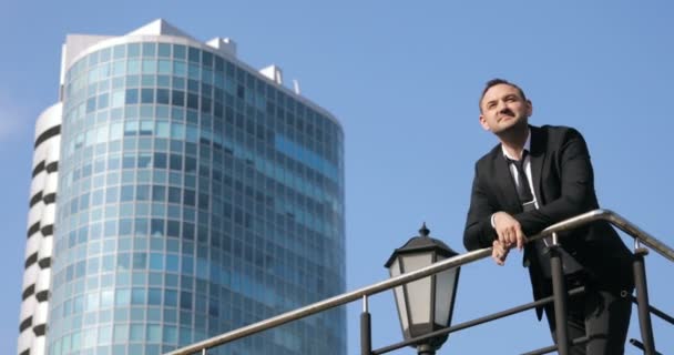 Successful businessman looks out at the view of the city skyline at day. A man on top of a building looking to city - Πλάνα, βίντεο