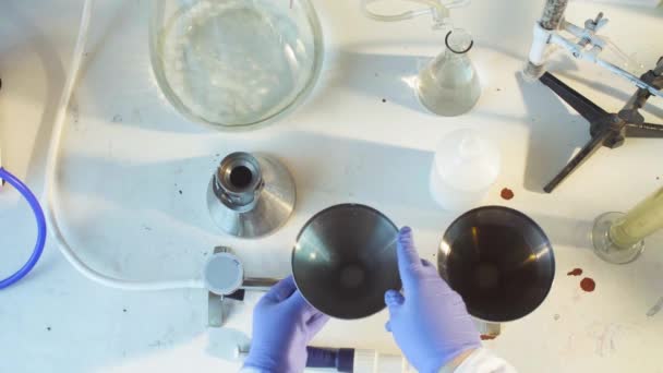 Tutkija laittaa suppilon tyhjiö suodatin
 - Materiaali, video
