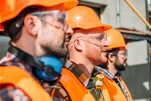 side view of group of equipped builders standing at construction site - Photo, Image