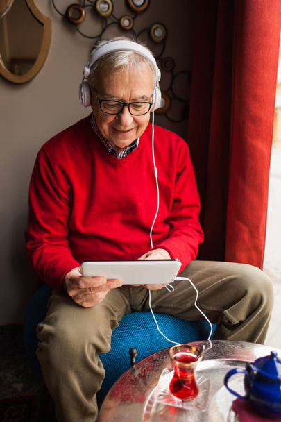 Портрет щасливого старшого чоловіка, який спілкується на цифровому планшеті в кафе
.  - Фото, зображення