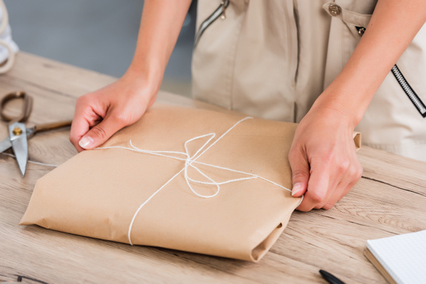 kadın moda tasarımcısı masada kağıt paket sarma kırpılmış görüntü  - Fotoğraf, Görsel
