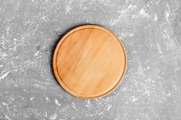 Empty round wooden dish on table over gray cement wall background, for product display montage. - Photo, Image