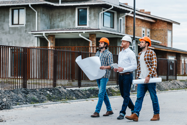 group of architects walking by building street with blueprints  - Φωτογραφία, εικόνα