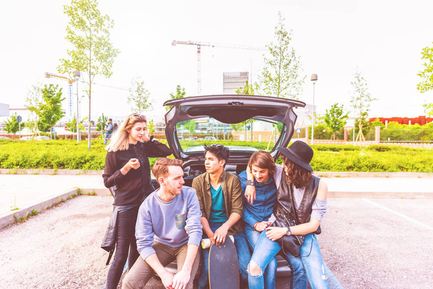 grupo de amigos multiétnicos sentados na bota do automóvel
  - Foto, Imagem