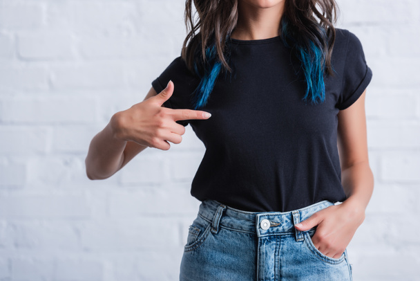 image recadrée d'une jeune femme pointant du doigt sur un t-shirt noir vide
  - Photo, image