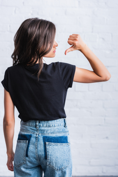 Selektywny fokus młoda kobieta wskazując palcem na odwrocie pusty czarny t-shirt  - Zdjęcie, obraz