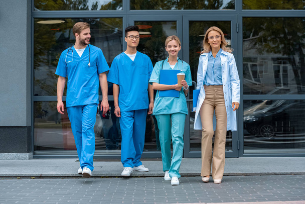 insegnante a piedi con gli studenti multiculturali presso l'università medica
 - Foto, immagini