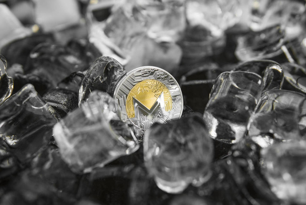 Digital currency physical metal gold monero coin on ice background. The concept of the exchange in winter. Freeze. Blockchain mining. Digital money and virtual cryptocurrency concept - Photo, image