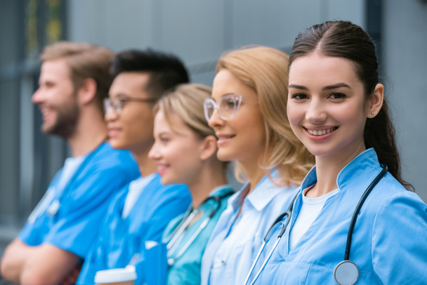 преподаватель и счастливые мультикультурные студенты, стоящие в ряд рядом с медицинским университетом
 - Фото, изображение